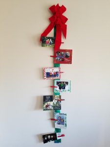 Easy Christmas Card display idea for your wall. Show off all your holiday cards with a wide ribbon, bow, wooden clothespins and some tape.