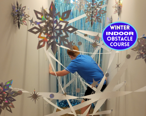 Create the ultimate winter indoor obstacle course for kids. A fun and easy rainy day activity ideas using white streamers and snowflakes to create a DIY laser maze in your hallway. A energy busting activity kids will love racing through the indoor maze!